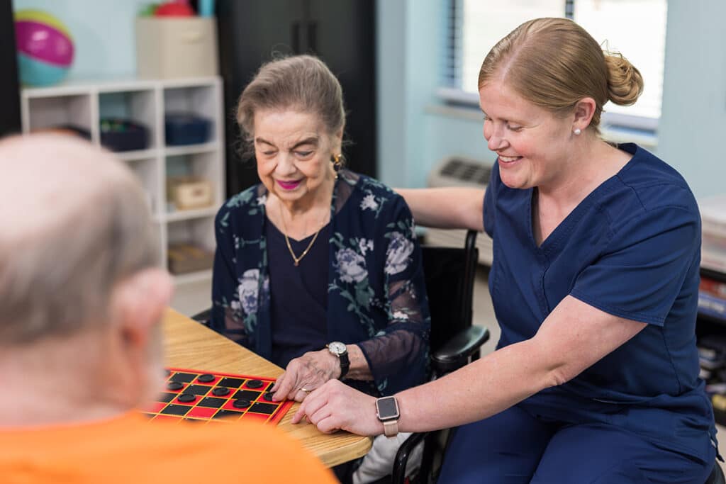 Nurse playing checkers with residents at Waverly Hills Post Acute